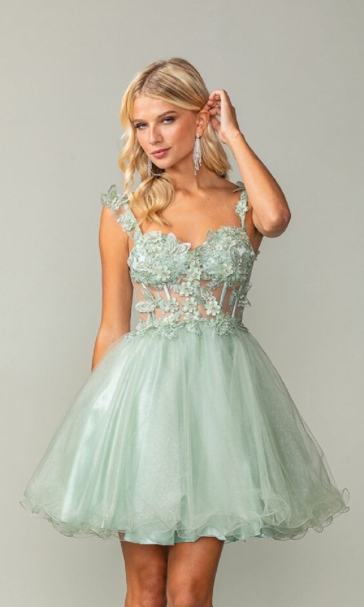Woman wearing a light green dress with floral lace details on a plain background